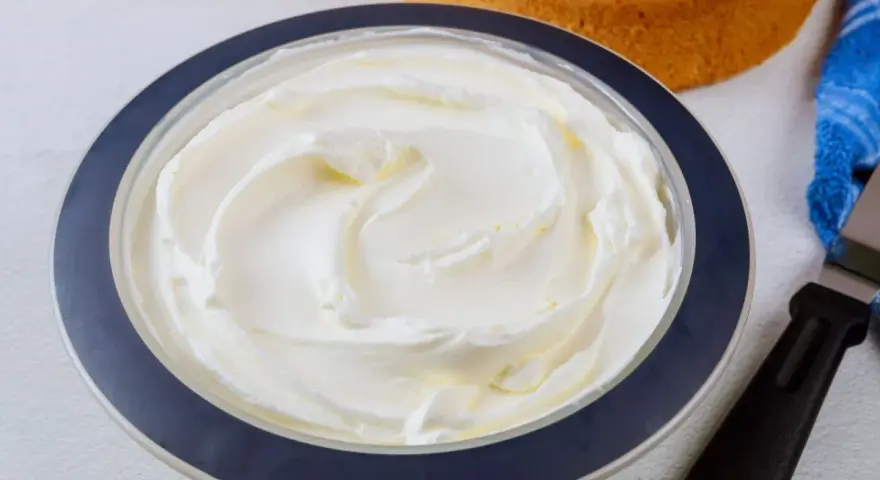 Puszysta bita śmietana z mascarpone w misce, gotowa do dekorowania biszkoptów.
