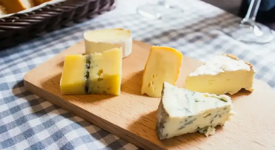 Deska z różnymi rodzajami serów, w tym ser typu włoskiego z niebieską pleśnią.