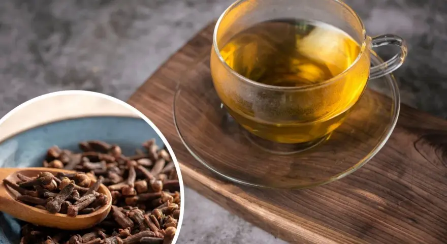 Napar z goździków przepis: aromatyczna herbata w szklance i miseczka pełna goździków na drewnianej desce.