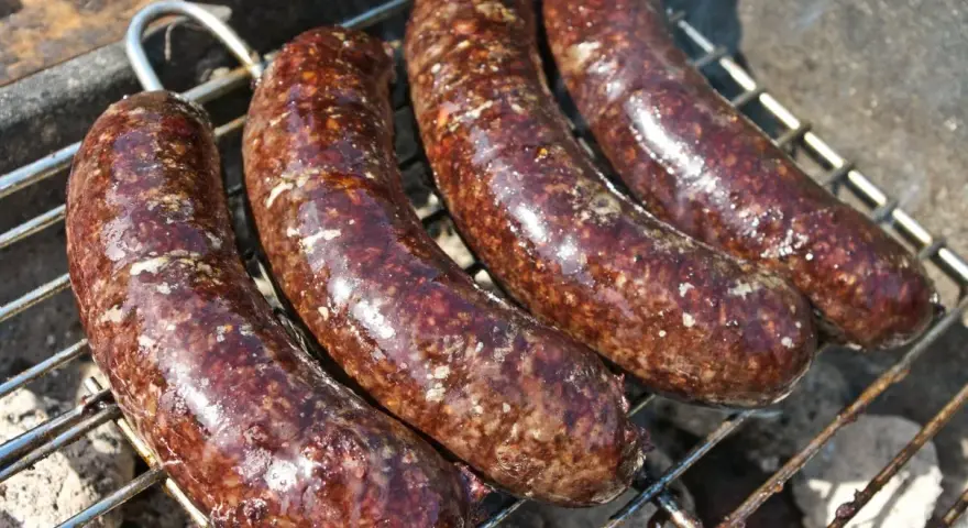 Cztery soczyste kaszanki na grilla, rumieniące się nad żarem. Idealne na letnie spotkanie.