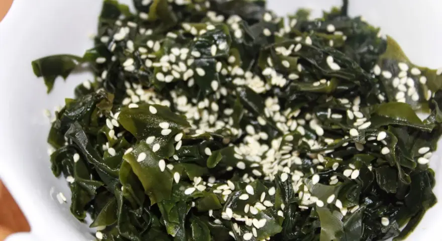Sałatka z wodorostów wakame, posypana sezamem. To pyszne i zdrowe danie, które warto spróbować, jeśli zastanawiasz się, wakame co to.