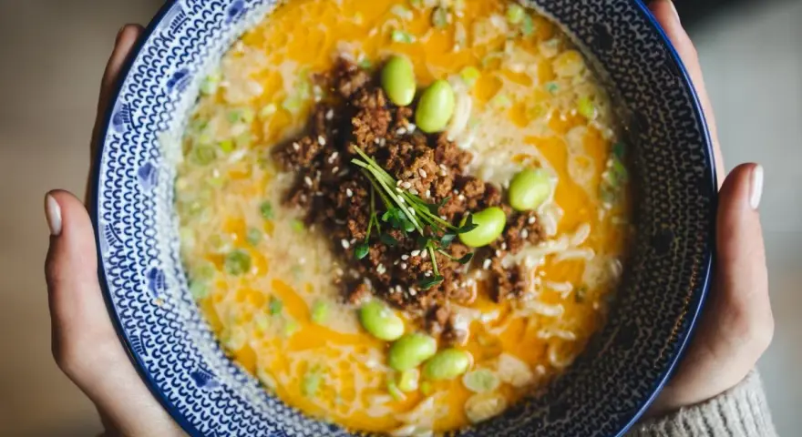 Miseczka tantanmen z mielonym mięsem, edamame i szczypiorkiem.