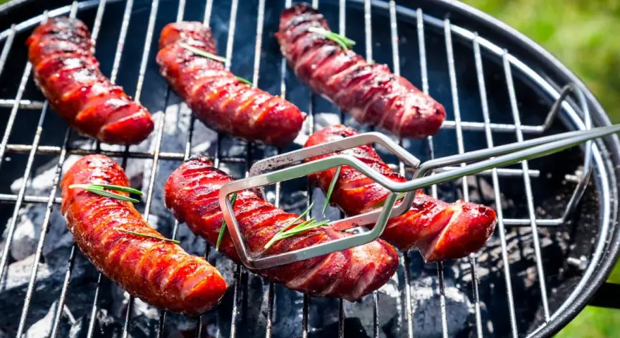 Soczysta kiełbasa na grilla, rumieniąca się nad żarem. Aromatyczny rozmaryn dodaje jej wyjątkowego smaku.