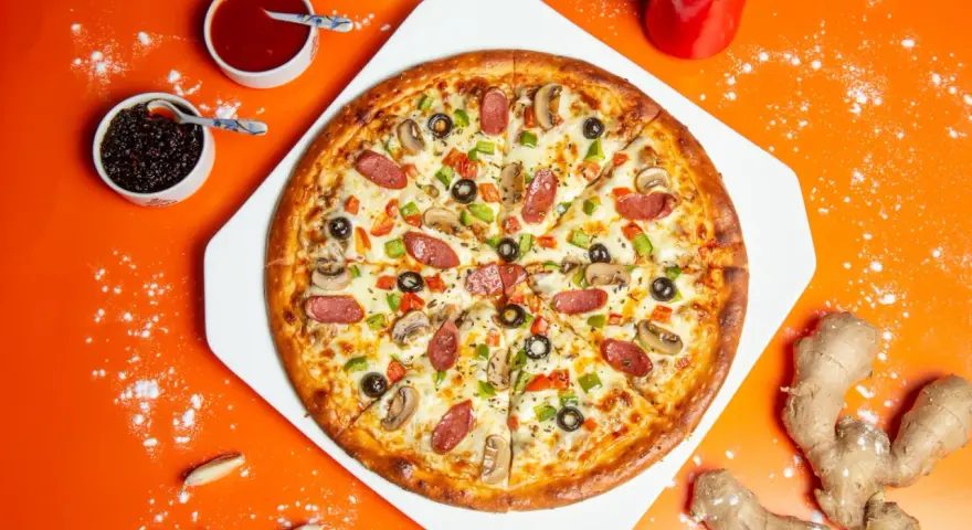 Pyszna pizza z kiełbasą, pieczarkami i papryką, obok sosy i imbir. Idealne dodatki do pizzy.