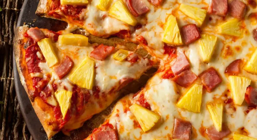 Pyszna pizza z ananasem i szynką, z ciągnącym się serem i chrupiącym ciastem. Idealna na szybki obiad.