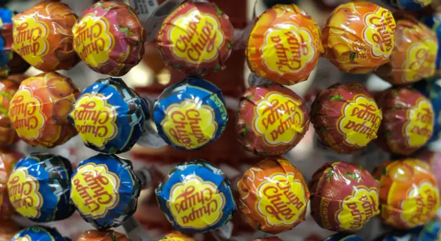 Zbliżenie na kolorowe lizaki Chupa Chups w opakowaniach z owocowymi wzorami.