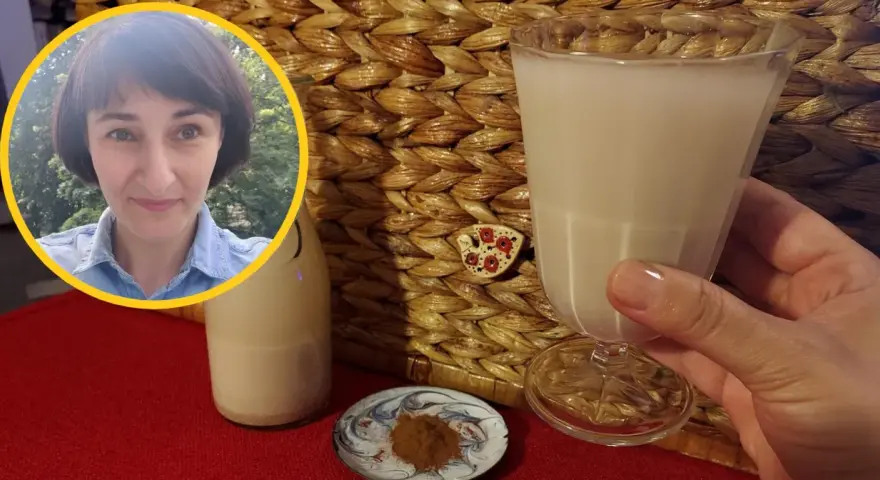 Kobieta z uśmiechem prezentuje szklankę z wodą owsianą, obok butelka i cynamon.