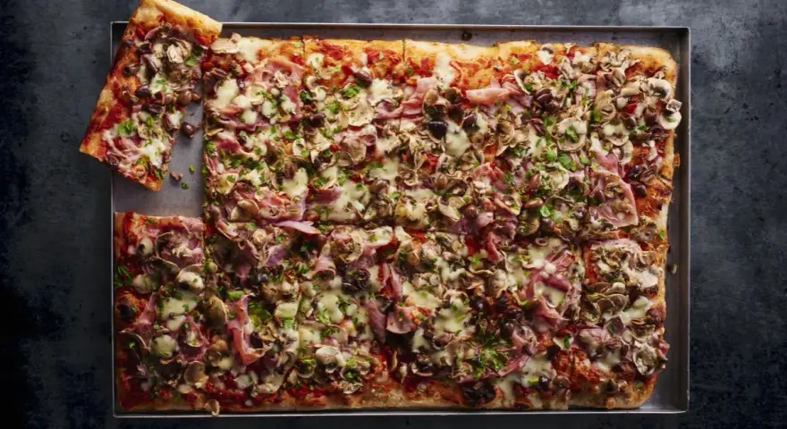 Najlepsza pizza domowa na dużą blachę, obficie posypana pieczarkami, szynką i oliwkami. Idealna na rodzinne spotkanie.