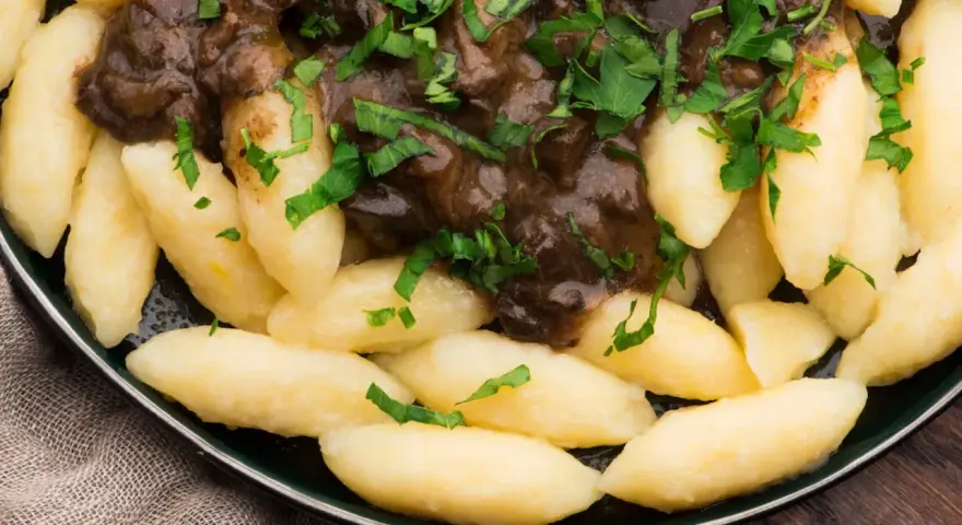Kopytka z gulaszem, jak u babci! Pyszne ciasto na kopytka przepis babci, polane aromatycznym sosem i posypane natką pietruszki.