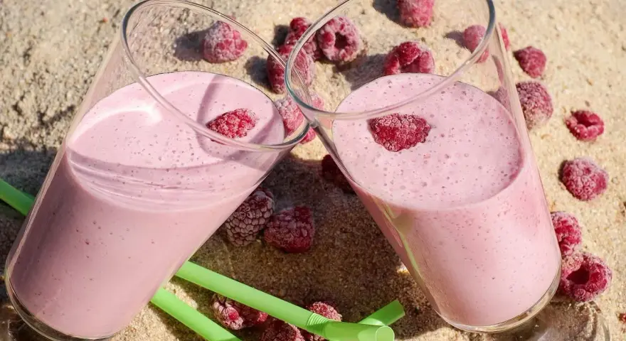 Dwa pyszne malinowe smoothie na piasku, idealne na lato. Inspiracja na zdrowe smoothie przepisy.