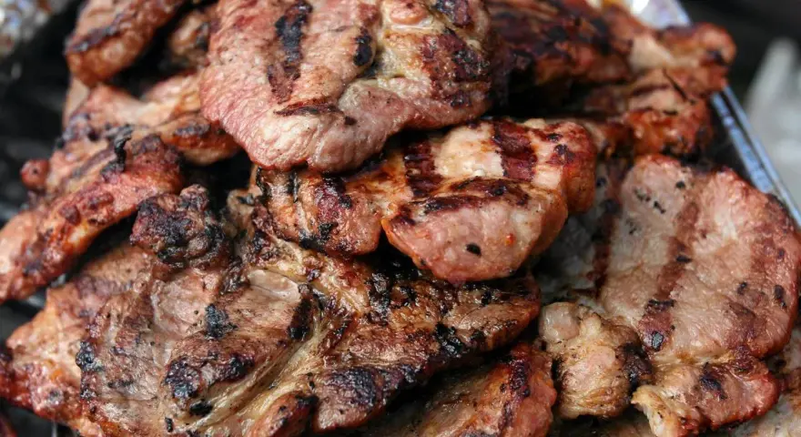 Soczysta karkówka z grilla, idealna po marynacie. Grillowane plastry mięsa z charakterystycznymi paskami.