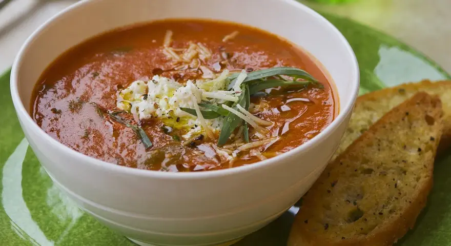 Aksamitna zupa solferino z serem feta i grzankami czosnkowymi na zielonym talerzu.