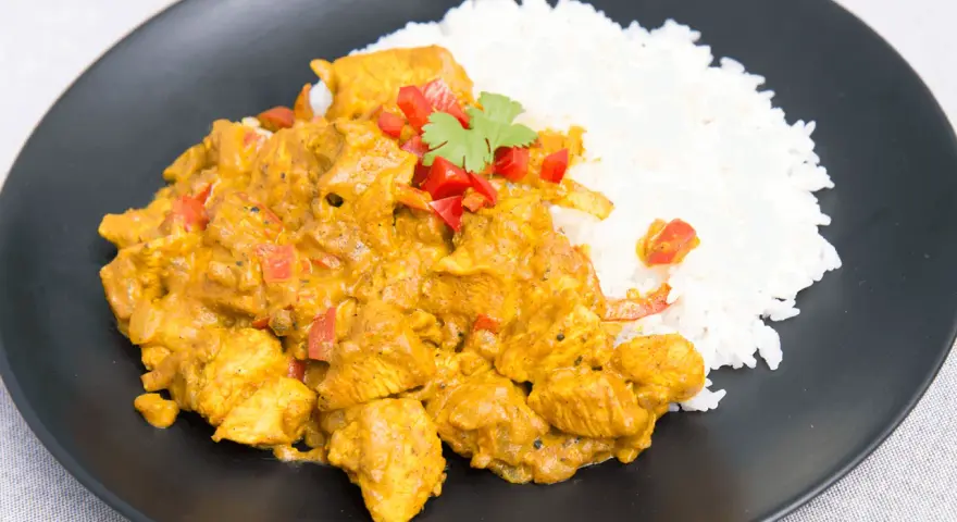 Kurczak w sosie curry z ryżem, posypany papryką i kolendrą. Prosty przepis na pyszny obiad.