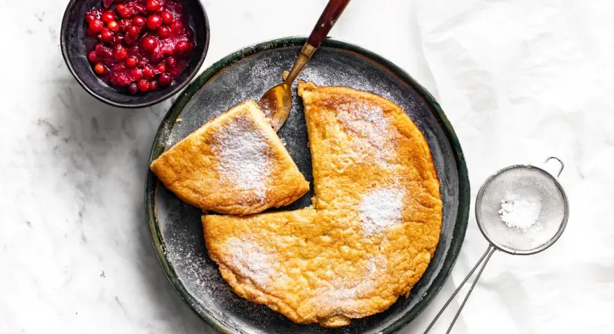 Puszysty omlet z air fryera, posypany cukrem pudrem, podany z żurawiną. Idealny na śniadanie.