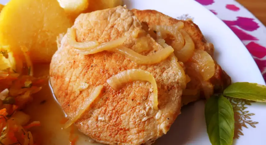 Pyszny schab w cebuli, idealny na niedzielny obiad, podany z ziemniakami i surówką.