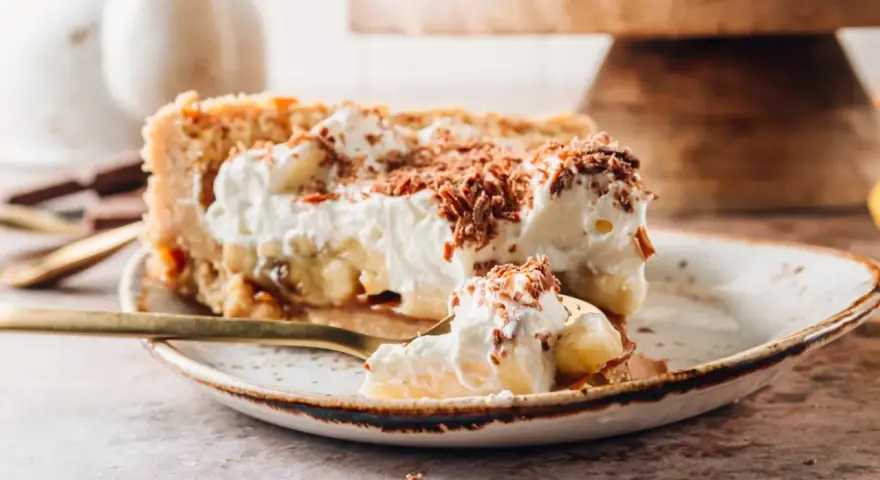Pyszne ciasto migdałowiec z bananami i bitą śmietaną, posypane czekoladą. Idealne na deser!