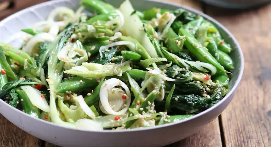 Sałatka z pak choi, groszku cukrowego i cebuli dymki, posypana sezamem. Idealna do dań kuchni azjatyckiej, świetne przepisy na kapustę pak choi.