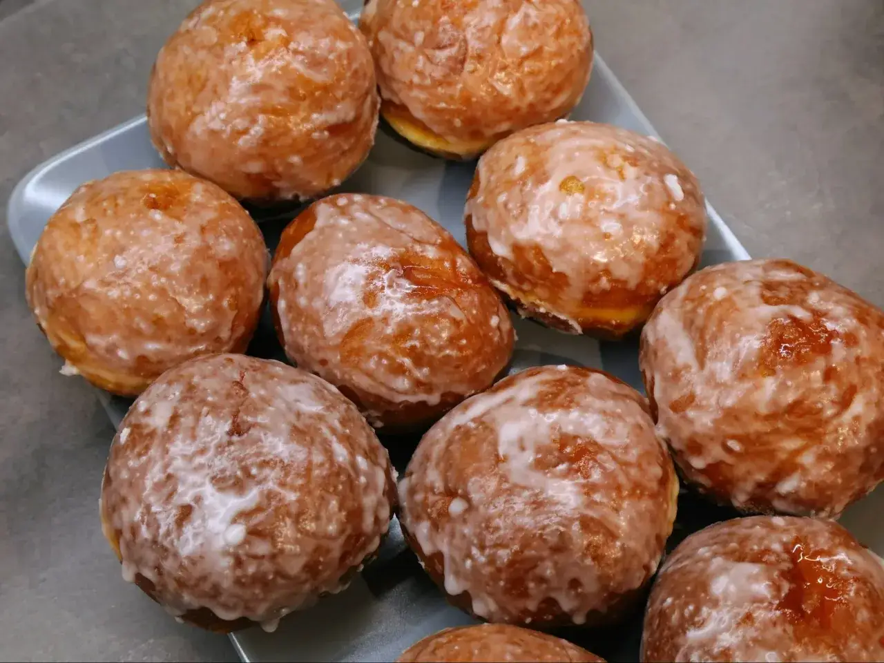 Szybkie pączki z piekarnika, oblane lukrem, kuszą apetycznym wyglądem. Idealne na szybką przekąskę.