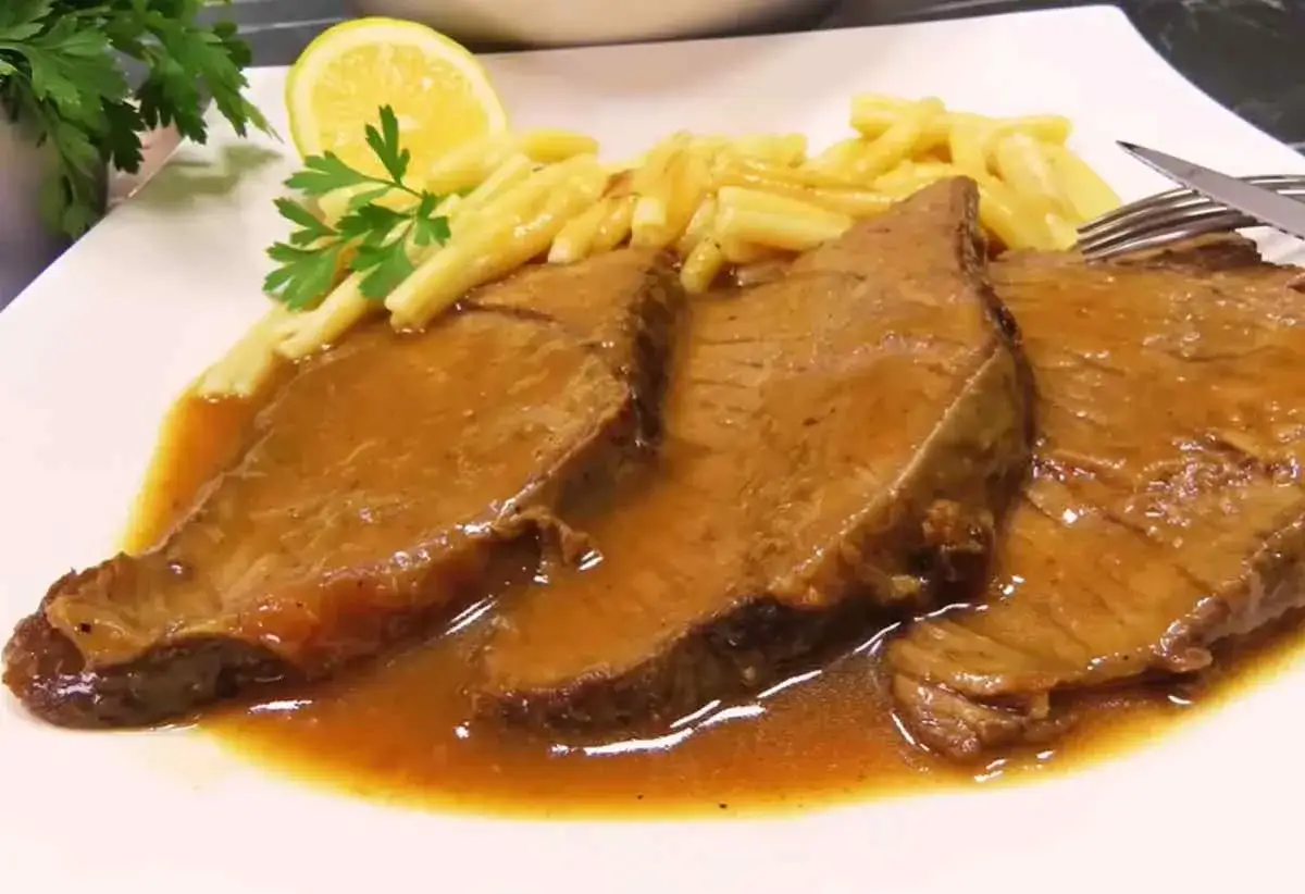 Soczysta łata wołowa w sosie, podana z makaronem i plasterkiem cytryny. Pyszny obiad gotowy!