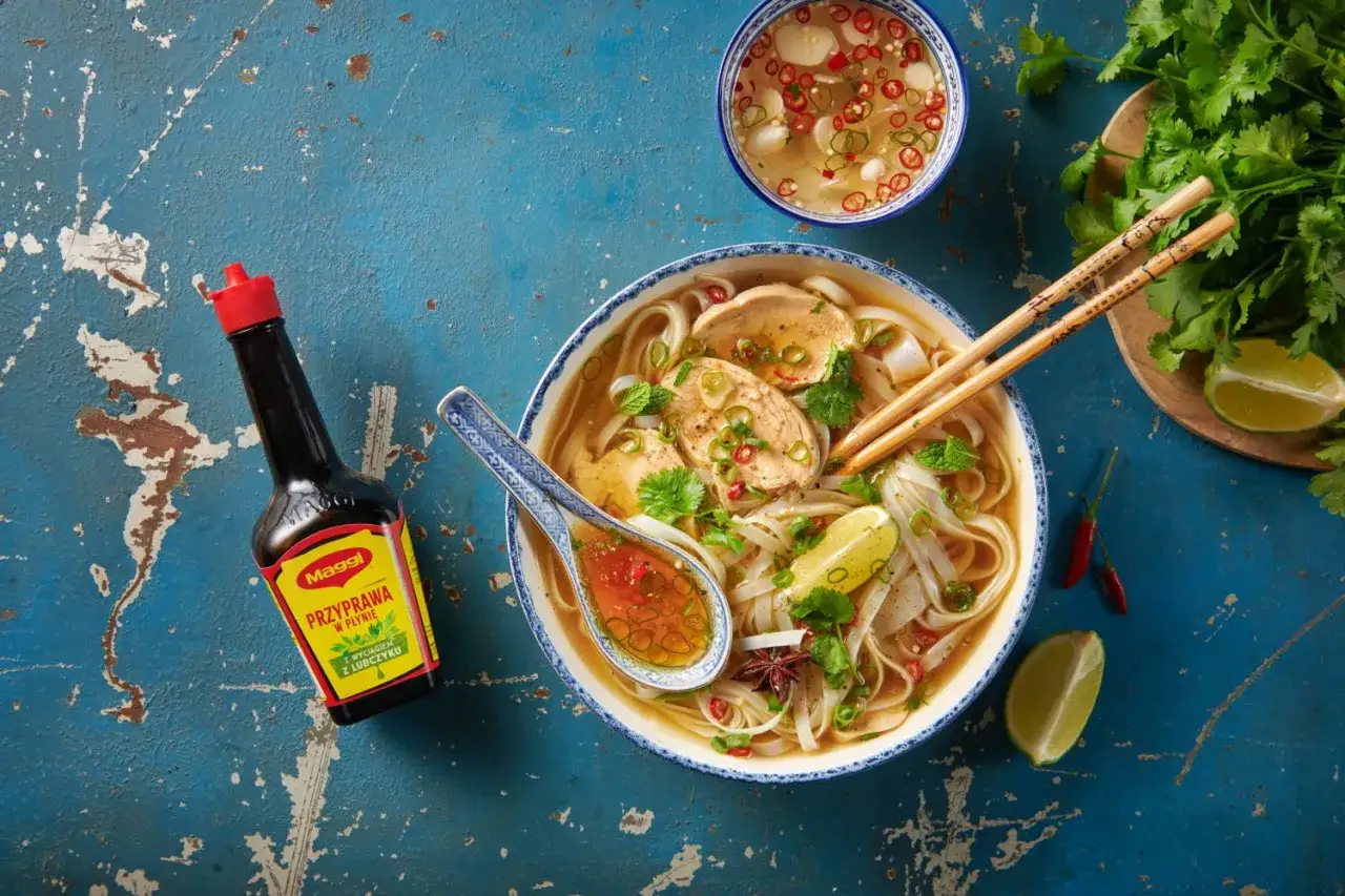 Aromatczne pho z kurczakiem, makaronem ryżowym, limonką i chili. Obok butelka przyprawy Maggi.