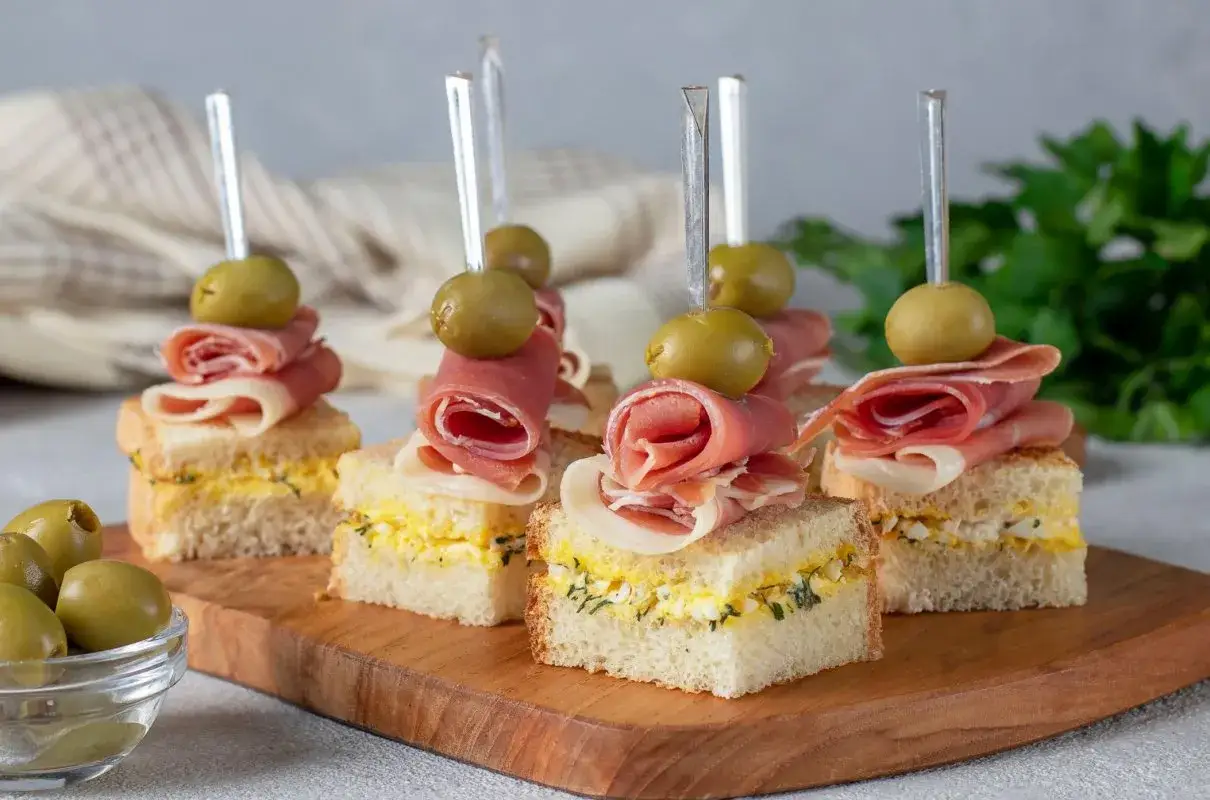 Mini kanapki z pastą jajeczną, szynką i oliwką na patyczku. Idealne finger food na przyjęcie.