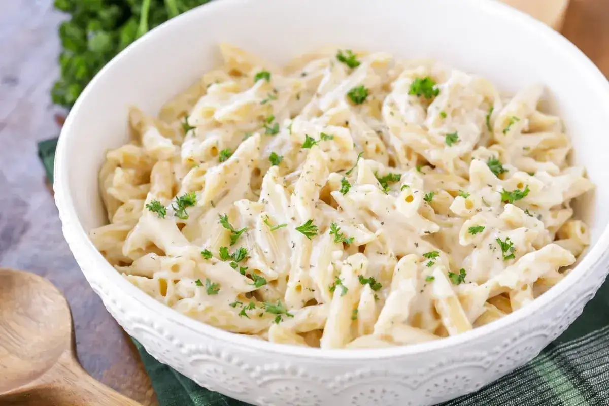 Penne w kremowym sosie śmietanowym, posypane natką pietruszki. Idealne danie na szybki obiad.