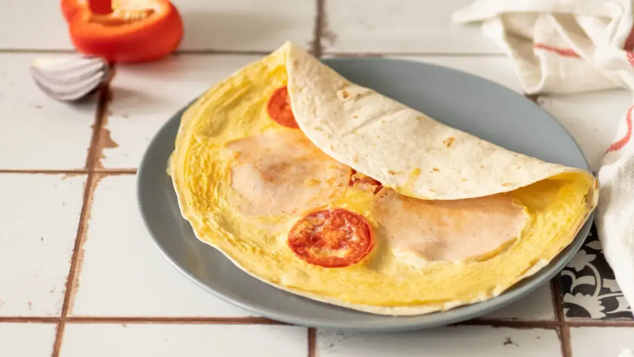 Tortilla z jajkiem, serem i szynką na patelni, z pomidorkami. Szybkie i pyszne śniadanie.