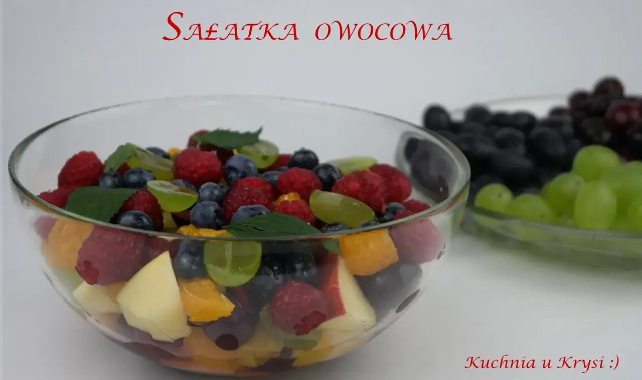Kolorowa sałatka owocowa w szklanej misie, pełna malin, borówek, winogron i pomarańczy. Idealne sałatka owocowa składniki na lato.