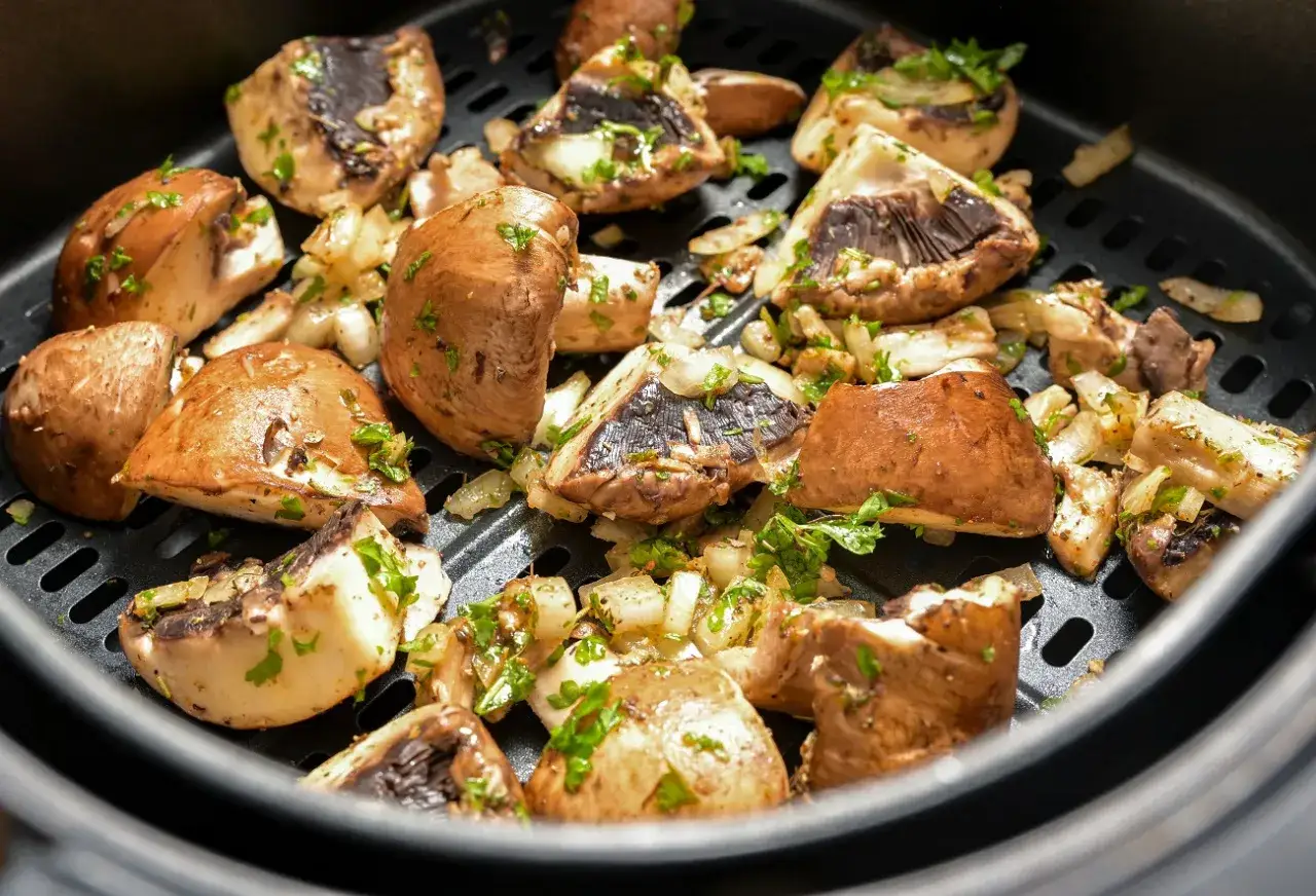 Pyszne pieczarki z airfryer, przyprawione i posypane natką pietruszki, gotowe do podania.