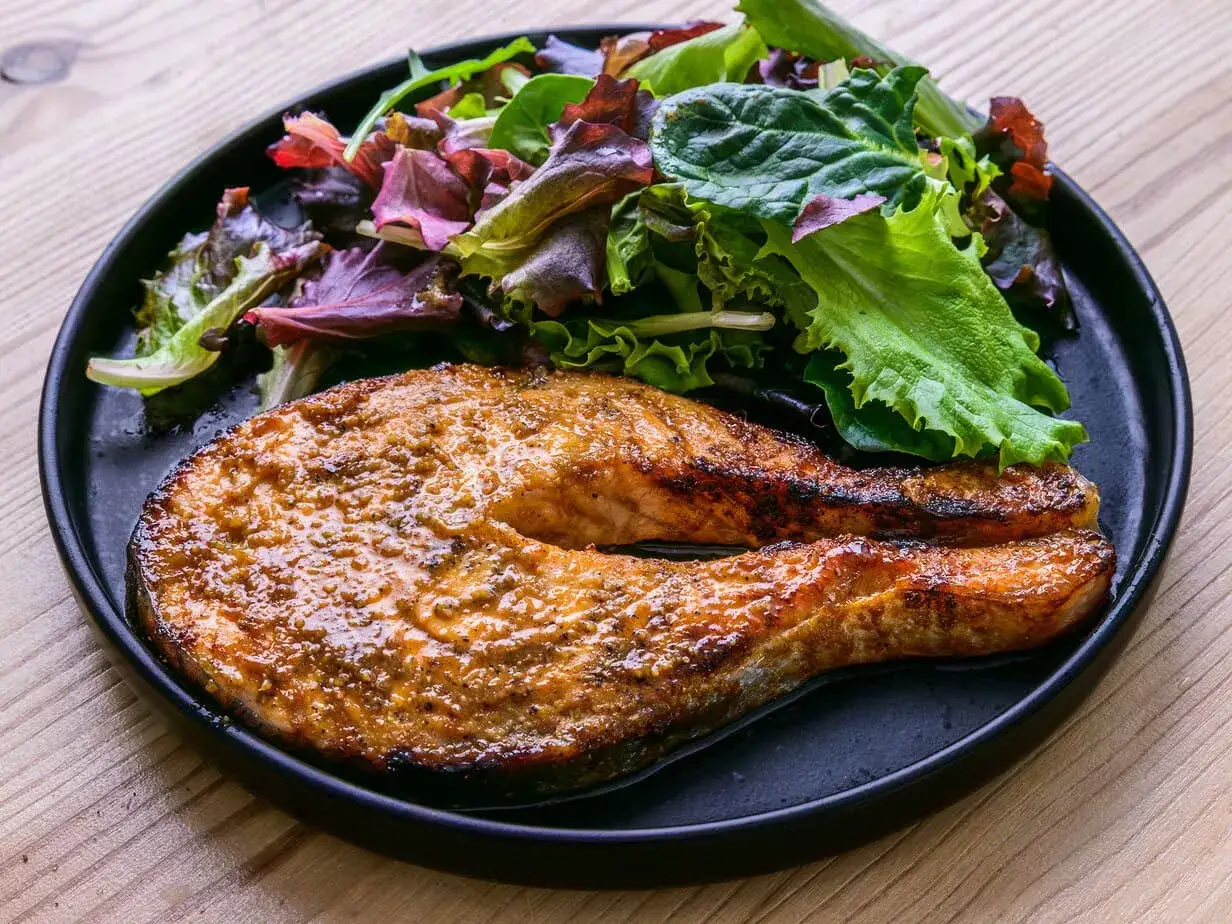 Soczysty łosoś z chrupiącą skórką i świeża sałatka na talerzu. Idealne danie z airfryer, które znajdziesz w airfryer przepisy po polsku.